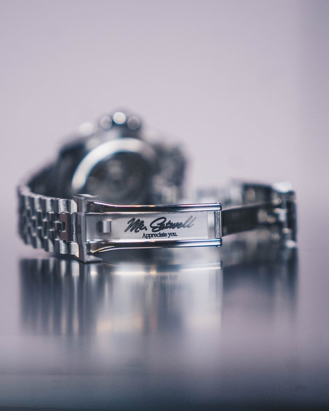 Macro of a steel bracelet clasp laser-engraved “Mr. Eatwell / Appreciate you.”